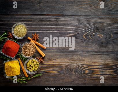 Set of spices and herbs on dark brown textured wooden table. Top view, empty space Stock Photo