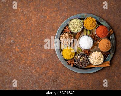 Mix spices on round metal plate - coriander, pepper, salt, rosemary, turmeric, curry. Top view, close up, copy space, metall rusty background. Stock Photo