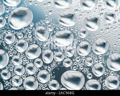 Abstract gray background with large and small spherical convex drops of water on glass. Bubbles on window. Macro, close up. Stock Photo