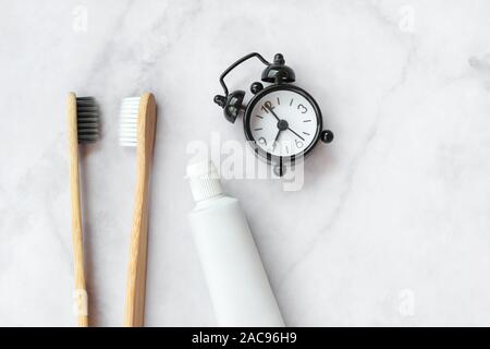 Set of eco-friendly toothbrushes, toothpaste, clock on marble background. Dental and healthcare concept. Top view, flat lay. Stock Photo