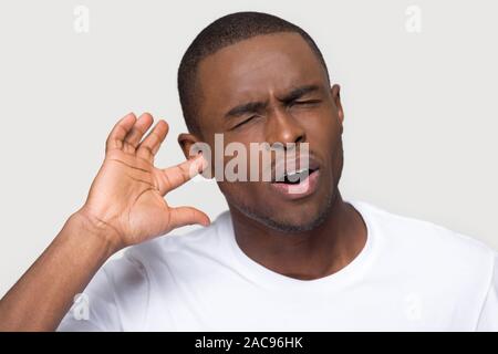 Unhappy African American man plug finger in ear, feeling pain Stock Photo