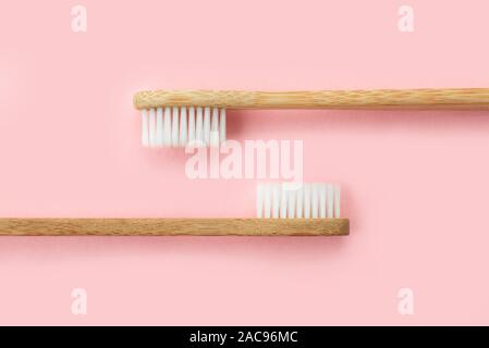 Two bamboo toothbrushes on pink background. Dental and healthcare concept. Top view, flat lay. Stock Photo