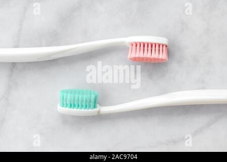 Two toothbrushes with pink and turquoise blue bristle on marble background. Dental and health care concept. Top view, flat lay. Stock Photo