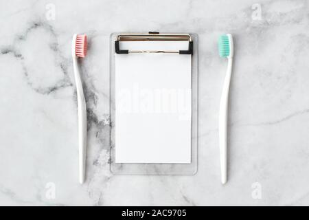 Set of pink and turquoise blue toothbrushes and empty note on marble background. Dental and health care concept. Top view, flat lay. Free copy space. Stock Photo