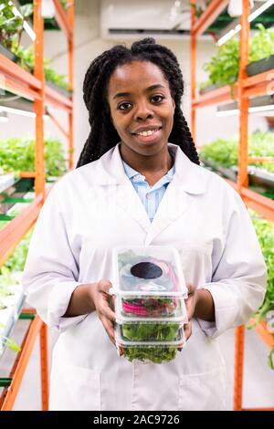 Successful African female agronomist holding stack of plastic containers Stock Photo