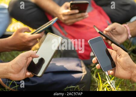 Close up of young people hands holding mobile - College Students addicted to smartphone - young millennials busy on cell phone - Group of friends Stock Photo
