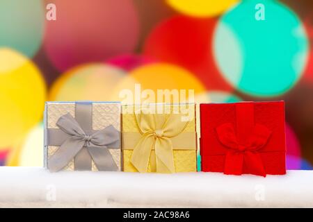 Colourful Gif boxes Presents on snow with a bokeh Background Stock Photo