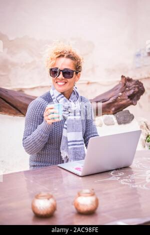 Digital nomad concept withfree. caucasian adult beautiful  woman working outdoor on a table with laptop computer internet connected - roaming device f Stock Photo