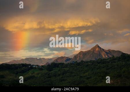Panama landscape with rainbow at sunrise in the interior of the Cocle province, Republic of Panama. The mountain Cerro Orari, 560 m, is to the right. Stock Photo