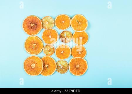 Bright colored dried oranges pattern on a blue background. The concept of homemade eco friendly Christmas decorations. Top viiew, flat lay, background. Stock Photo