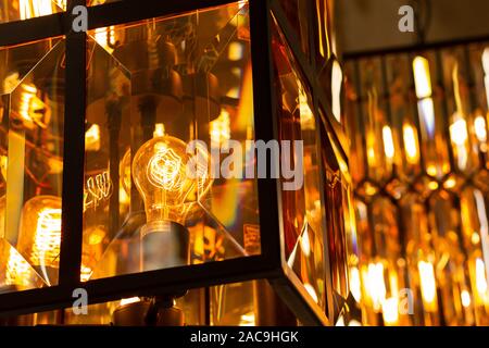 Edison retro light bulb with yellow light in an industrial black metal glass lamp post Stock Photo