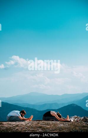 Find you balance, find yourself. Beautiful young couple doing acro yoga in nature Stock Photo