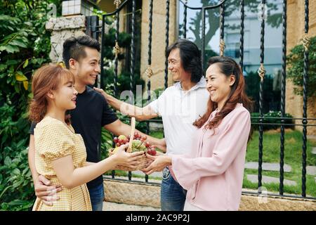 Happy young Asian man and his girlfriend coming to house of his mature parents Stock Photo