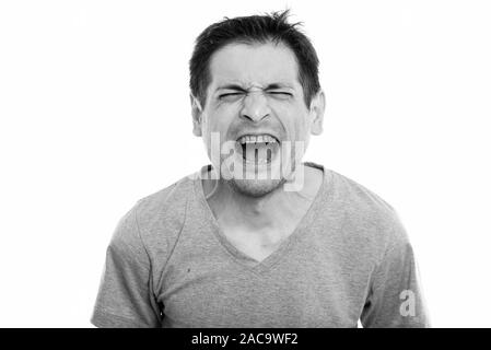 Studio shot of angry young man screaming with eyes closed Stock Photo