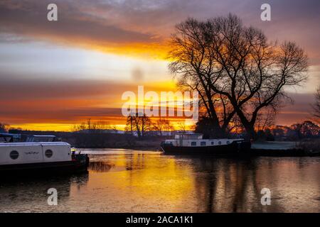 Rufford, Lancashire, UK. 2nd Dec, 2019. A cold Christmas in prospect for houseboat residents at Rufford Marina, with temperatures well below freezing in rural Lancashire smoke from morning fires forms a light haze above the waterway.  Houseboats residents at St Mary's Marina, on the Leeds Liverpool canal, waking to purple skies and a glorious sunrise.Credit:MediaWorldImages/AlamyLiveNews Stock Photo