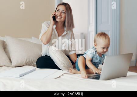 Business mom talking on a cell phone. Multi-tasking, freelance and motherhood concept Stock Photo