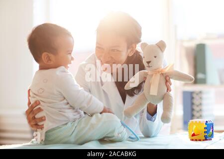 Young female doctor smiling and playing with baby boy during her visit Stock Photo
