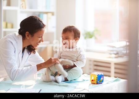 Female doctor playing with her little patient while examining him at hospital Stock Photo