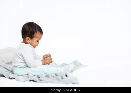 Cute African baby boy sitting on blanket and playing with toys isolated on white background Stock Photo