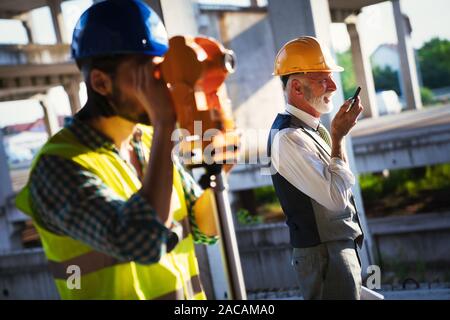 Confident team of architects and engineers working together on construction site Stock Photo
