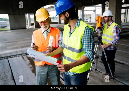 Two satisfied engineers talking at building site with construction structure in background Stock Photo