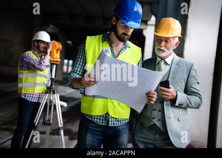 Male architects analyzing blueprint at construction site Stock Photo