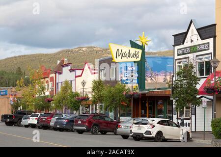 Stores on Main Street in Whitehorse, the Yukon, Canada. Vehicles park on the street. Stock Photo