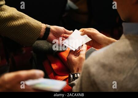 Two people hand over business cards at a meeting Stock Photo