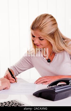Woman signs a contract in an office