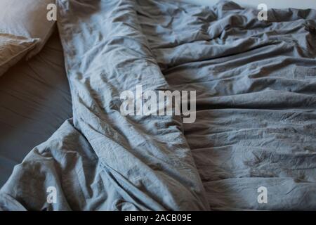 A gray cotton sheet and blankets with pillows on the bed Stock Photo