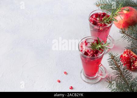 Two glass of pomegranate Christmas holiday cocktail with rosemary, cranberry, champagne, club soda on grey table. Xmas drink. Space for text. Stock Photo