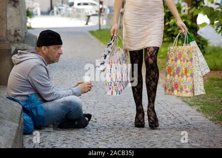 Beggar and rich woman with shopping bags Stock Photo