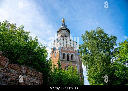 A tall tower against a blue sky, surrounded by green trees. Stock Photo