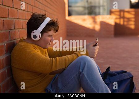 Teenage boy sitting in school grounds Stock Photo