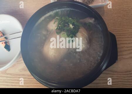 view from above on boiling steamy Samgyetang - ginseng chicken soup, meaning ginseng - chicken - soup in Korean, consists primarily of a whole young c Stock Photo