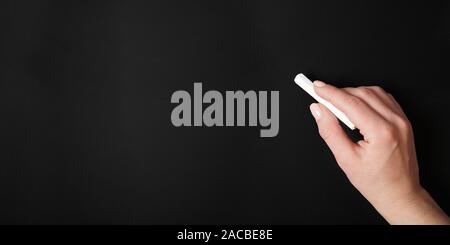 female hand against blank chalk board background Stock Photo