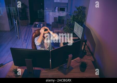 Oh no. Hign angle view photo of it specialist loser guy sitting chair many monitors noticed server debugging holding hands on head need to edit errors Stock Photo