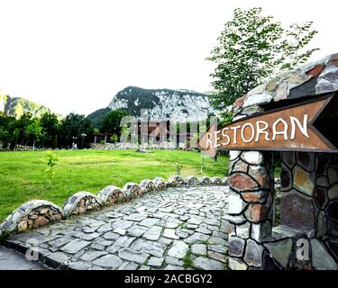 wooden arrow pointer restaurant, green grass and mountain view Stock Photo
