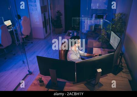 Profile photo of it specialist guy night sitting chair seriously looking many monitors writing secure code for website calculate algorithms content Stock Photo
