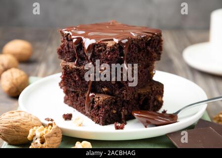 Chocolate spongy brownie cakes with walnuts and melted chocolate topping on a stack Stock Photo