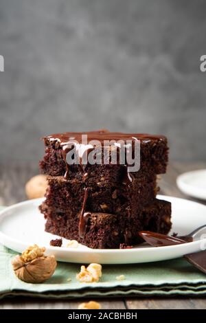 Chocolate spongy brownie cakes with walnuts and melted chocolate topping on a stack Stock Photo