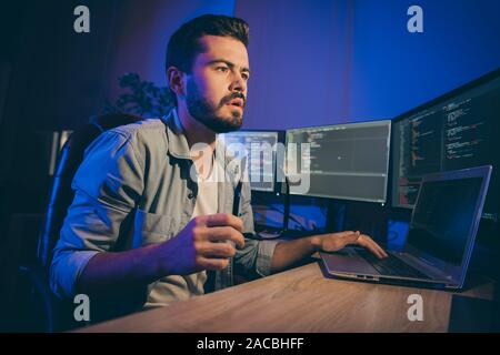 Profile photo of it specialist guy working late at night sitting office chair looking monitors website debugging expert have problems service error Stock Photo