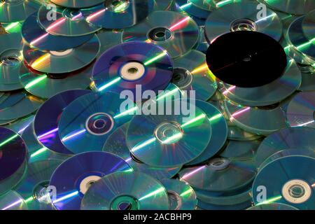 A pile of CDs and DVDs. The surface of the discs reflects light Stock Photo