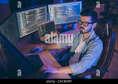 Portrait of his he nice attractive focused brunette guy creating script coding java html mysql database using languages software hard-working at dark Stock Photo