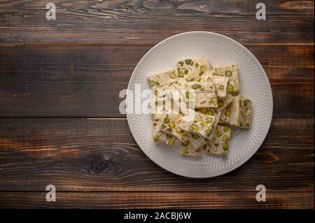 Eastern Arabic nougat sweetness with pistachios on a ceramic plate on a light background. Top view Stock Photo