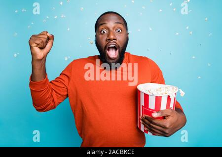 Photo of speechless stunned crazy handsome funny man shocked about plot twist of movie he watches holding bucket isolated in rain of pop corn over Stock Photo