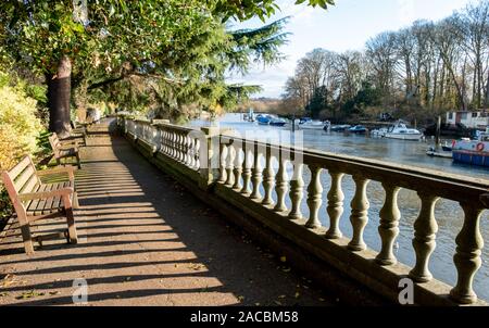 Path beside the River Thames at Twickenham, London UK, photographed in strong sun on a fine winter's day. Balustrade create sshadows. Stock Photo
