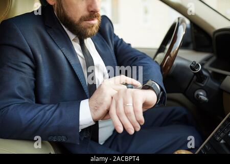 Close-up of man looking at his watch on his hand while sitting in his car he hurrying to a meeting Stock Photo