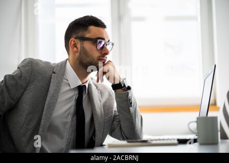 Young pensive businessman is working in office. Stock Photo