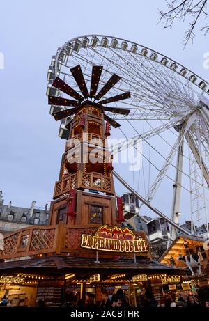 PARIS, FRANCE - NOVEMBER 30, 2019: giant wooden tower and a big wheel in the background in the Christmas Market at the Tuileries Garden in Paris. Stock Photo